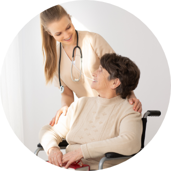 A young woman with a stethoscope around her neck tending to an elderly woman in a wheelchair.